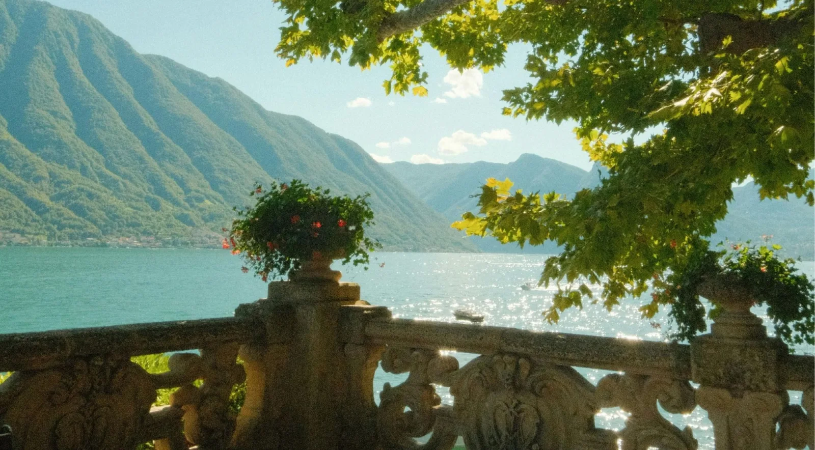 The stone balustrade and flower urns of Villa del Balbianello framed by a plane tree above Lake Como