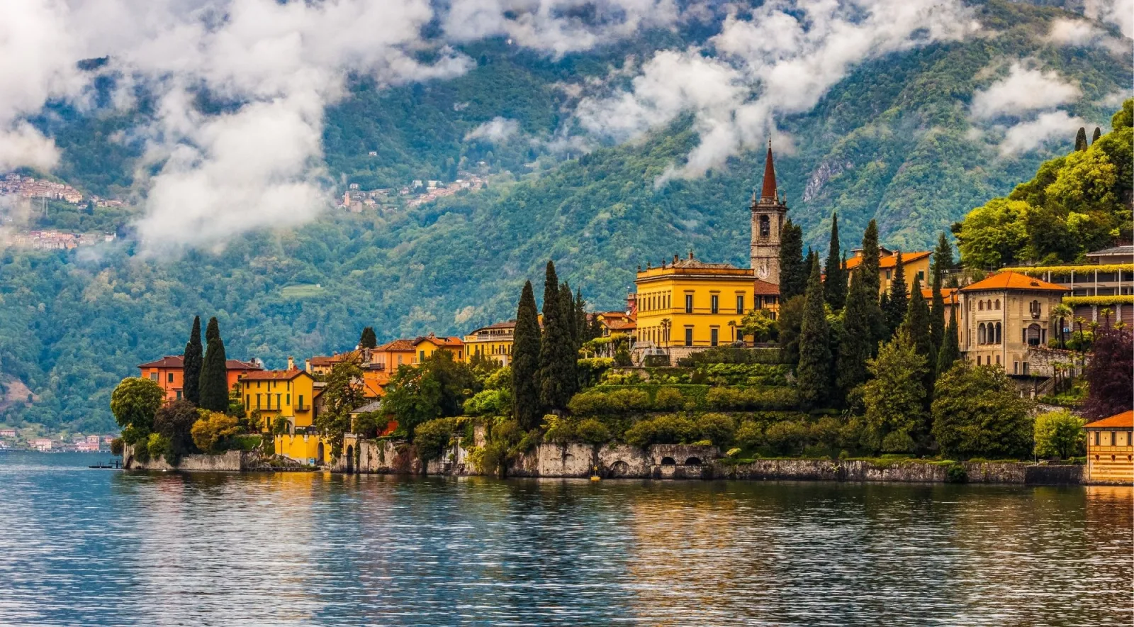 Varenna's pastel houses and church spire below mist-wrapped mountains on Lake Como