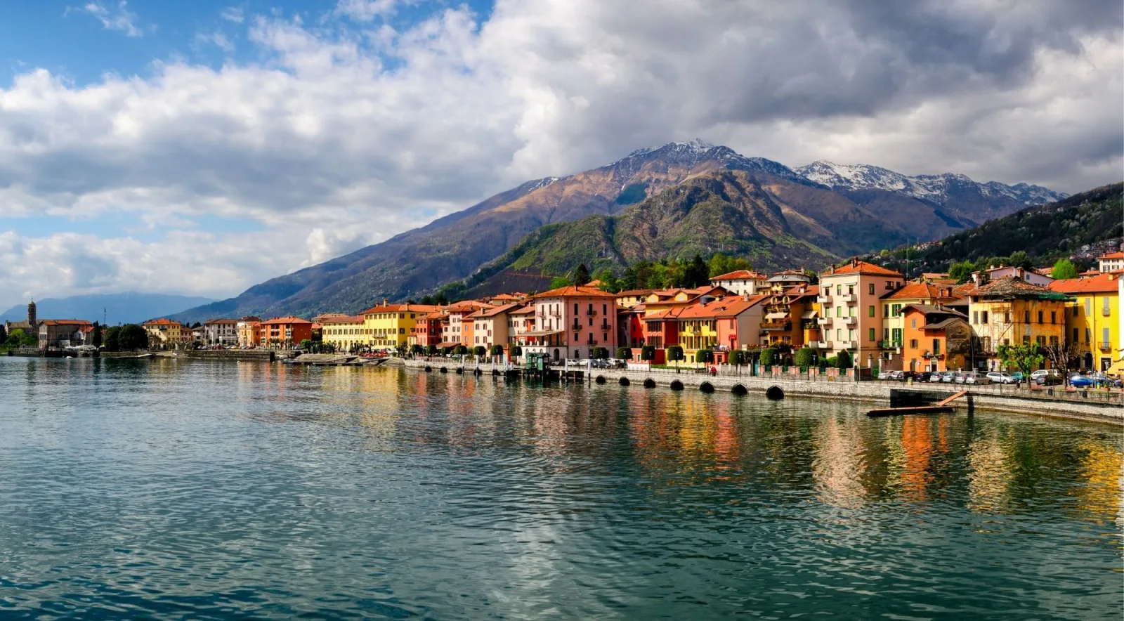 The colourful lakefront town of Gravedona reflected in Lake Como beneath a snow-dusted peak